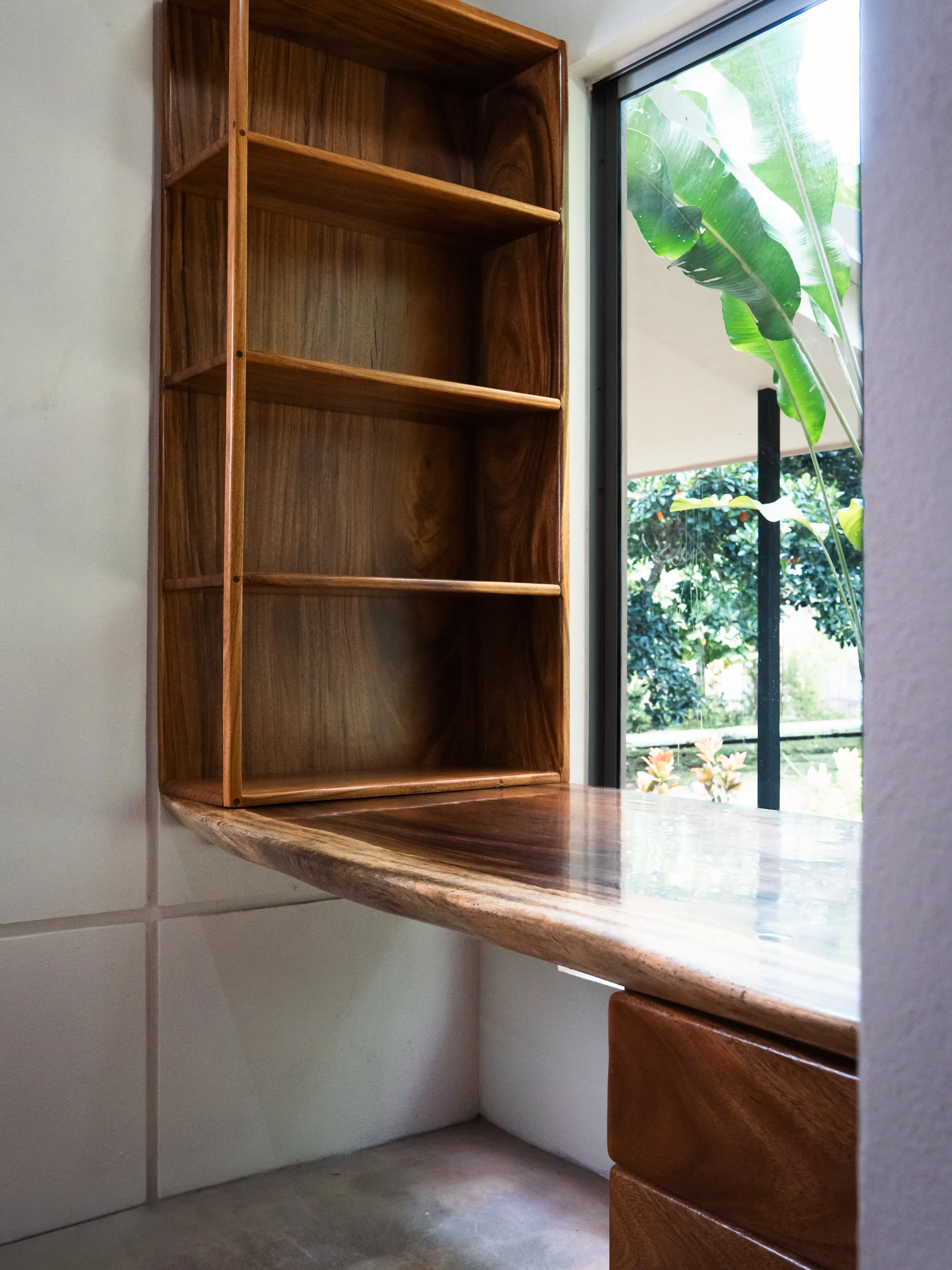 Escritorio flotante y estantería de Guanacaste macizo junto a la ventana
